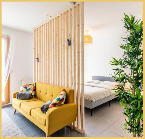 a living room with a yellow couch and a bed at Appartement T2 Proche Genève Beaumont in Beaumont