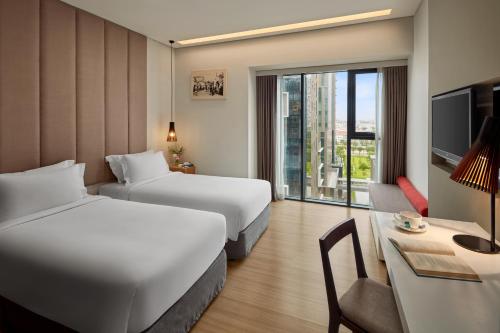 a hotel room with two beds and a desk at Novotel Living Saigon South in Ho Chi Minh City