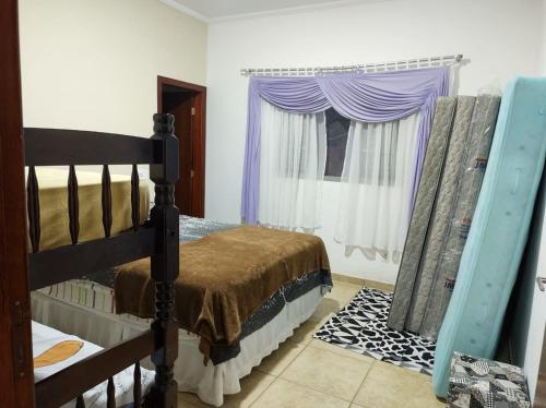 - une chambre avec un lit et une fenêtre avec des rideaux violets dans l'établissement Chácara dos Teixeira, à Socorro
