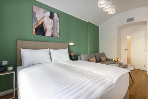 a large white bed in a room with green walls at Hidden Art Boutique Residence by Dwellfort in Prague
