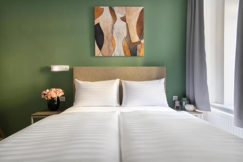 a bedroom with a white bed with a green wall at Hidden Art Boutique Residence by Dwellfort in Prague