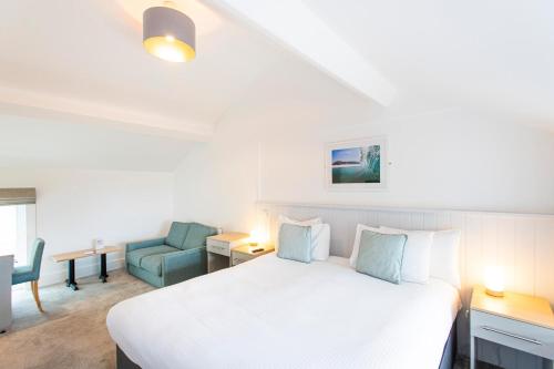 a bedroom with a white bed and a blue chair at Tregenna Castle Resort in St Ives