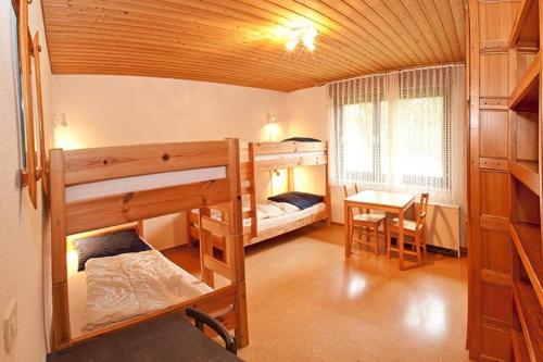 a room with two bunk beds and a table and a desk at Feriendorf Reichenbach - Wieselweg 7 in Nesselwang