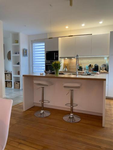 une cuisine avec un comptoir et deux tabourets de bar dans l'établissement La Villa les merlettes, au Crotoy