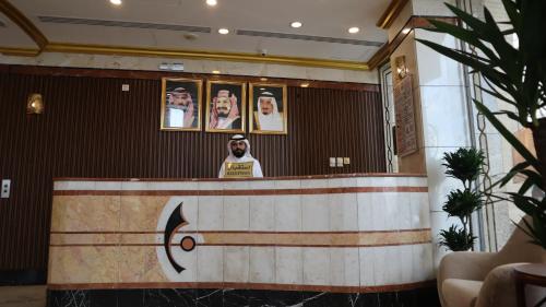 Un homme debout derrière un comptoir dans une pièce dans l'établissement Al Mukhtara Almasi Hotel, à Médine