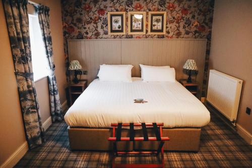 a bedroom with a bed with two chairs and a window at The Knaresborough Inn - The Inn Collection Group in Knaresborough