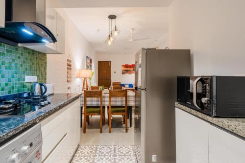 a kitchen with a refrigerator and a dining room at HideAway 2BHK Villa Style Apartment - Stay To Unwind in Old Goa