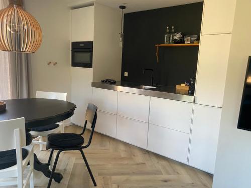 a kitchen with white cabinets and a table with chairs at B&B Het Zwarte Schaap in Albergen