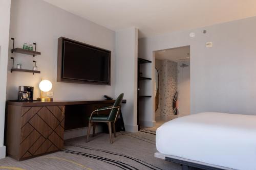 a bedroom with a bed and a desk with a television at The Starling Atlanta Midtown, Curio Collection by Hilton in Atlanta