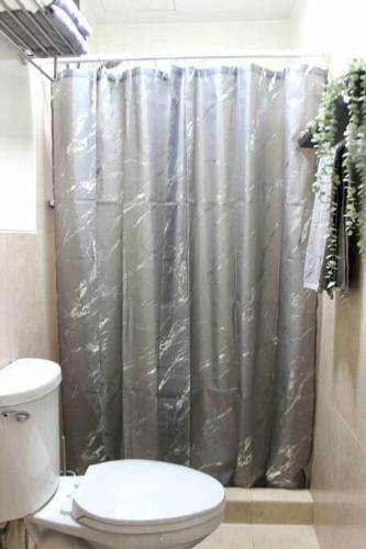 a bathroom with a toilet and a shower curtain at La Vida Hermosa in Manila