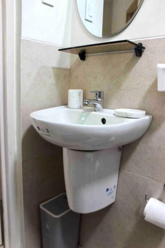 a bathroom with a white sink and a mirror at La Vida Hermosa in Manila