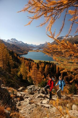 two people standing on a mountain looking at a lake at Hotel Spöl Restaurant in Zernez