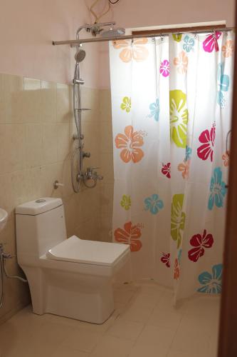 a bathroom with a toilet and a shower curtain at Kuttralam Resorts in Kuttālam