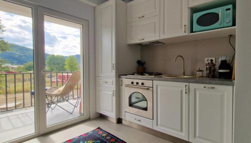 Una cocina con estufa y microondas y un balcón. en Neo Rustic Bucovina, en Gura Humorului
