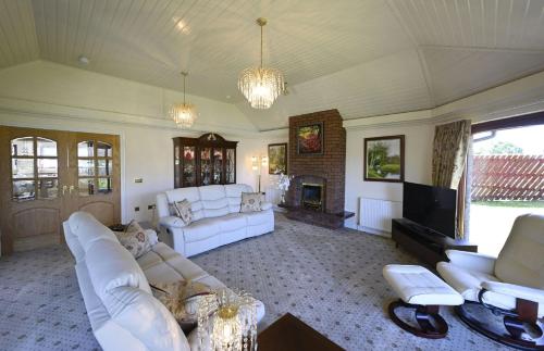 a living room with white furniture and a fireplace at Hillcrest in Fort William
