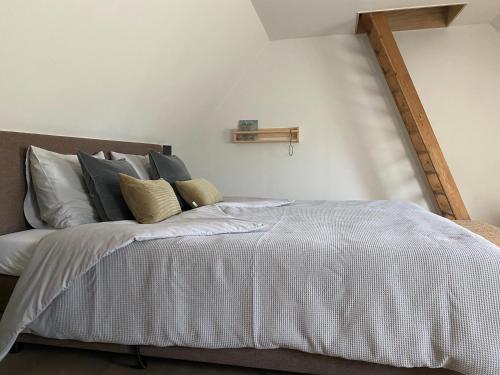 1 dormitorio con 1 cama con sábanas y almohadas blancas en B&B Het Zwarte Schaap en Albergen