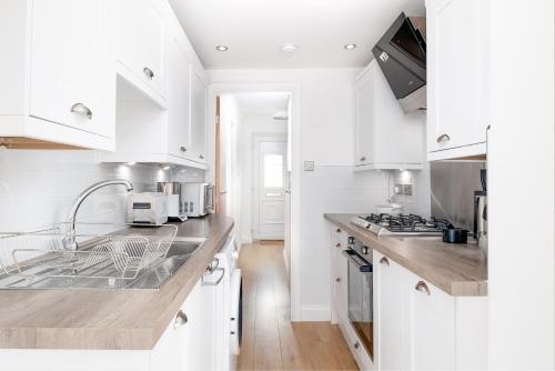 a white kitchen with white cabinets and a sink at The High Trees by Night Stay in Birmingham