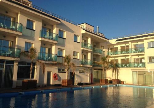 un hotel con piscina frente a un edificio en Hotel Port Sitges en Sitges