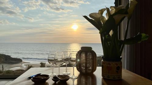 einen Tisch mit Weingläsern und eine Vase mit Blumen in der Unterkunft Agua de Madeiros - Vista do mar in Pedra Do Ouro