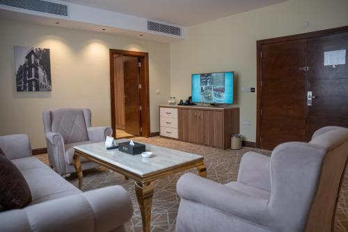 a living room with chairs and a table and a tv at Rosemond Al Hamra in Jeddah