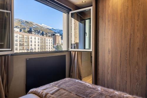 a bedroom with a window with a view of a city at TODOSIERRANEVADA ZONA BAJA - 2 DORMITORIOS DELUXE REFORMADO - JUNTO A LOS TELECABINAS in Sierra Nevada