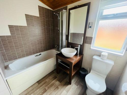 La salle de bains est pourvue d'une baignoire, d'un lavabo et de toilettes. dans l'établissement Crystal Lodge with Hot Tub, à Malton