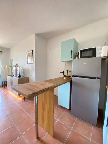 une cuisine avec une table en bois et un réfrigérateur dans l'établissement Cocon aux portes du centre ville avec terrasse, à Avignon
