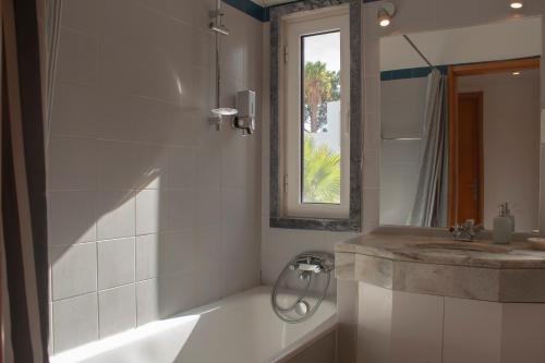 a bathroom with a sink and a shower and a mirror at Refúgio Sol Tróia in Troia