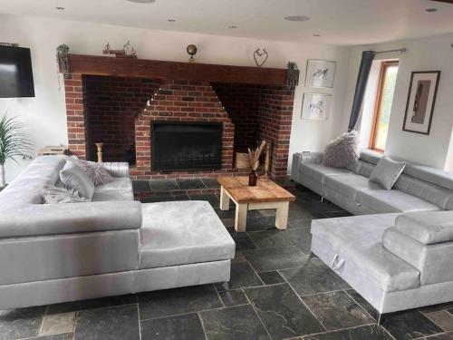 a living room with couches and a brick fireplace at 10 sleeper beautiful house with 8 seat hot tub! in Durley