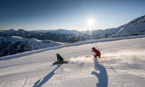 two people are skiing down a snow covered slope at Apartments Monika - Altenmarkt in Altenmarkt im Pongau