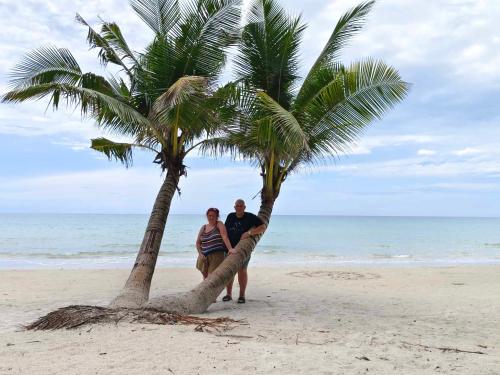a man and woman standing under a palm tree on the beach at Mateoasis in Ko Kood