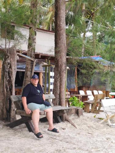a man sitting on a bench on the beach at Mateoasis in Ko Kood