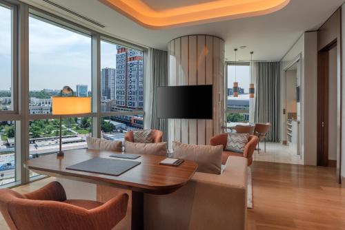 a living room with a table and chairs and a large window at Hilton Tashkent City in Tashkent