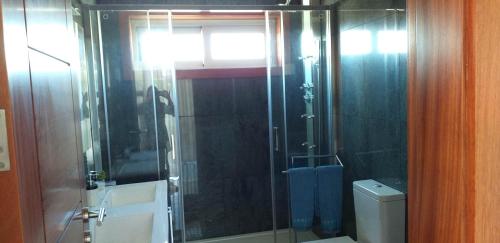 een badkamer met een glazen douche en een toilet bij Casa do Chino 