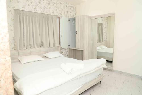 a white bedroom with a bed and a mirror at Dnyanprabha Executive in Tuljapur