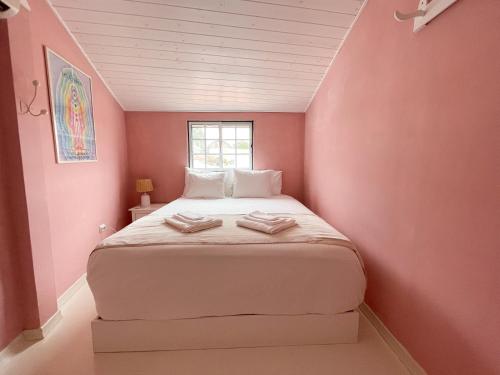 a small bedroom with a bed in a pink wall at Charming Countryside Home with Fireplace & Patio in Alcoutim