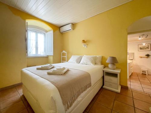 a bedroom with a white bed and a yellow wall at Charming Countryside Home with Fireplace & Patio in Alcoutim