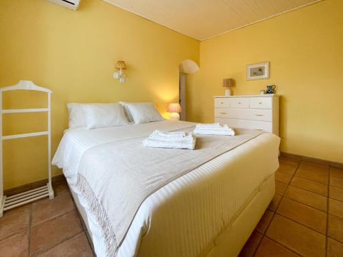 um quarto com uma grande cama branca com paredes amarelas em Charming Countryside Home with Fireplace & Patio em Alcoutim