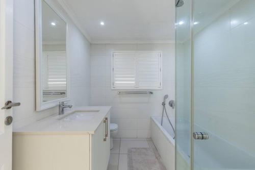 een witte badkamer met een wastafel en een douche bij 7 Kenwyn On Sea in Ballito