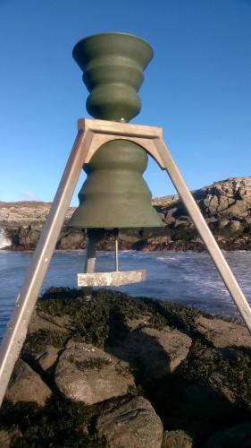 a large green bell sitting on top of some water at Harsgeir View Holiday Cottage -Wifi Go green in Breaclete