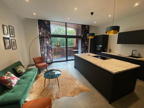 a living room with a green couch and a kitchen at Les Quais de la Vesdre in Verviers