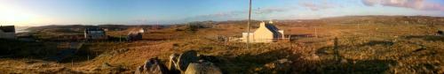 a view of a hill with a white building on it at Harsgeir View Holiday Cottage -Wifi Go green in Breaclete
