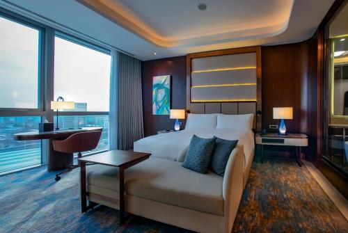 a hotel room with a bed and a desk and windows at Hilton Tashkent City in Tashkent