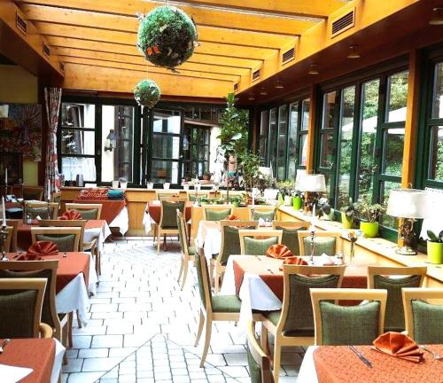 un restaurante con mesas, sillas y ventanas en Hotel Restaurant - Häuserl im Wald Graz, en Graz