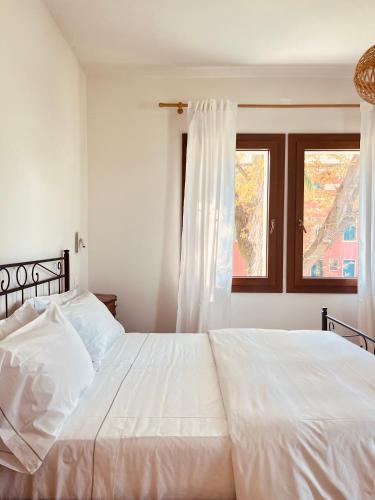 a white bed in a bedroom with a window at Agriturismo Borgo Rurale San Salvador-Casa del Maestro in Torre di Mosto