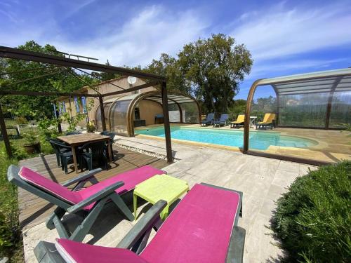 eine Terrasse mit Stühlen, einem Tisch und einem Pool in der Unterkunft Maison au calme piscine mer au coeur de la nature U Nuciolu in Talasani