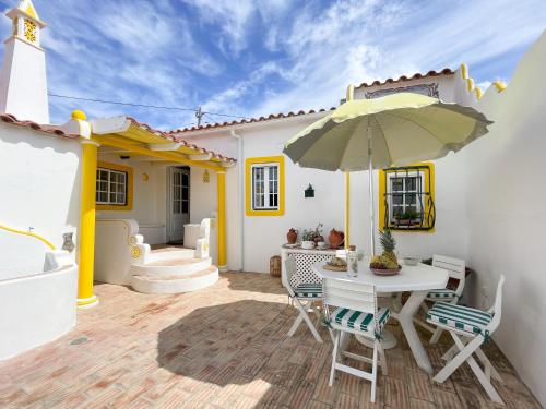 阿爾科廷的住宿－Charming Countryside Home with Fireplace & Patio，庭院配有桌椅和遮阳伞。