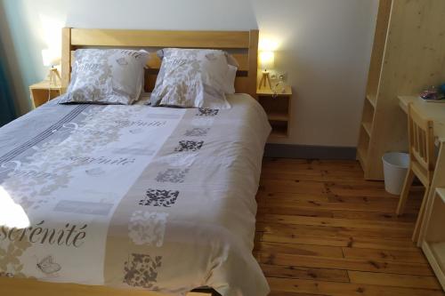 Schlafzimmer mit einem Bett mit weißer Bettwäsche und Holzböden in der Unterkunft Chartreuse in Saint-Franc