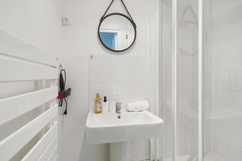 La salle de bains blanche est pourvue d'un lavabo et d'un miroir. dans l'établissement Chic apart downtown Paris, à Paris