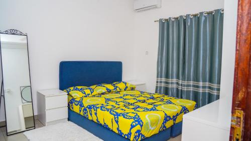 una camera con letto blu e giallo e specchio di MUSA SILLAH a Sukuta